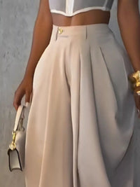 Beige high-waisted pants worn by a person against a gray background