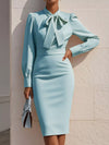 Light blue dress with a large bow detail worn by a person against a neutral background