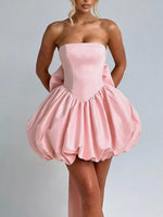 Pink strapless dress worn by a model on a plain background