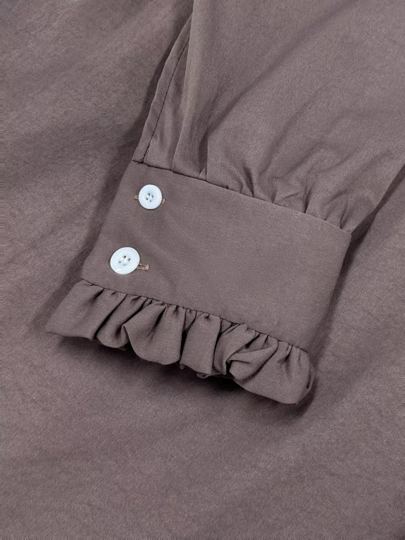 Brown fabric with ruffled hem and buttons on a matching background