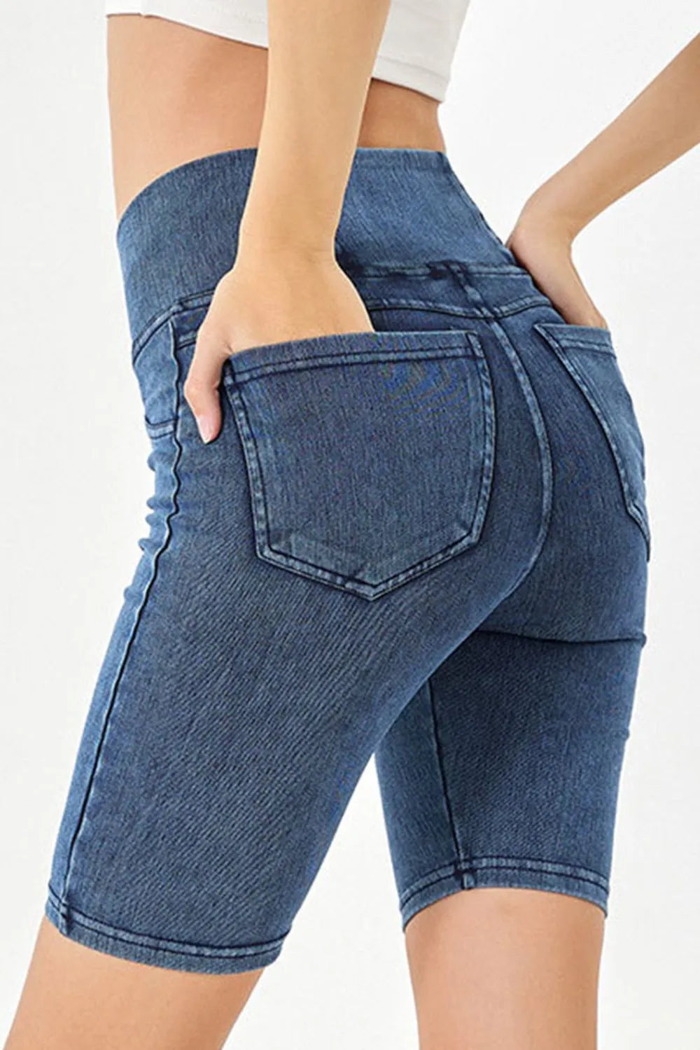 Blue denim shorts worn by a person on a white background