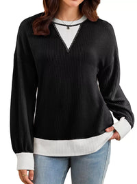 Woman wearing a black and white sweater with blue jeans on a white background