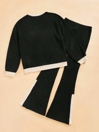 Black ribbed knit outfit with white trim on a beige background