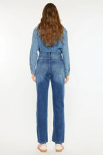 Person wearing a blue denim jumpsuit on a white background