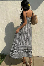 Woman wearing a black and white patterned dress against a textured wall.