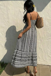 Woman wearing a black and white patterned dress against a textured wall.