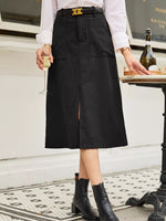 Person wearing a black skirt with a white shirt and black boots, holding a glass.