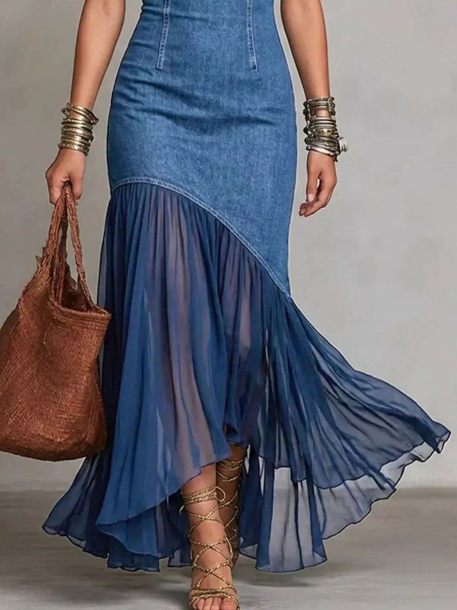Woman wearing a blue denim dress with a sheer overlay, holding a brown bag.
