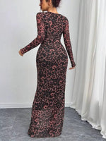 Person wearing a long, sheer dress with a leopard print pattern in a room with white walls and curtains.