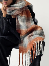 Person wearing a plaid scarf with orange and gray tones on a white background