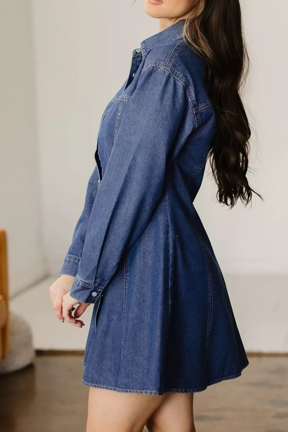 Woman wearing a denim dress in a minimal indoor setting