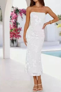 Woman wearing a strapless white lace dress with a blurred floral and pool background
