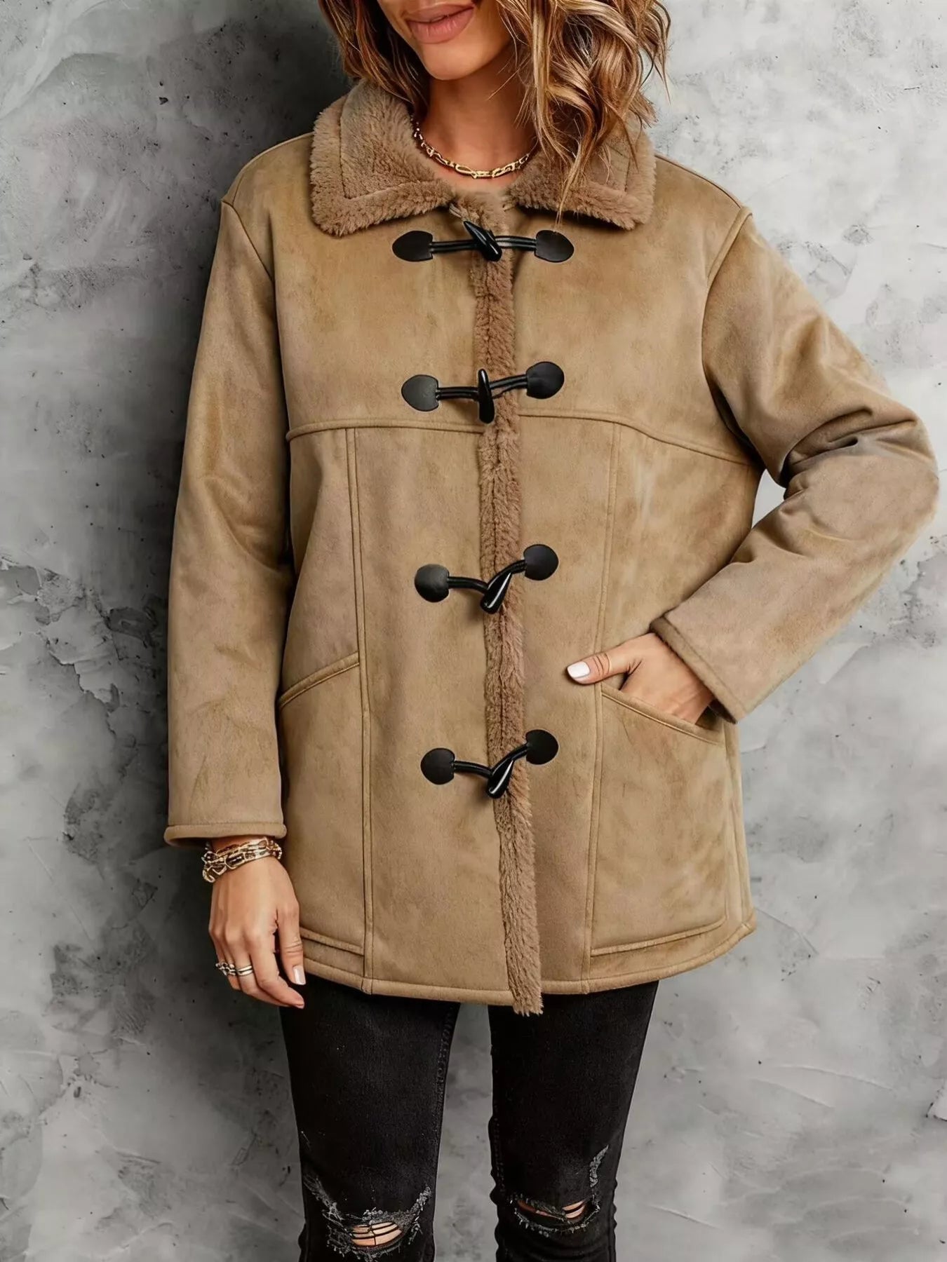 Person wearing a beige duffel coat with black buttons against a gray background