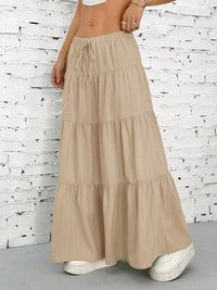 Beige tiered skirt worn by a person against a white brick wall.