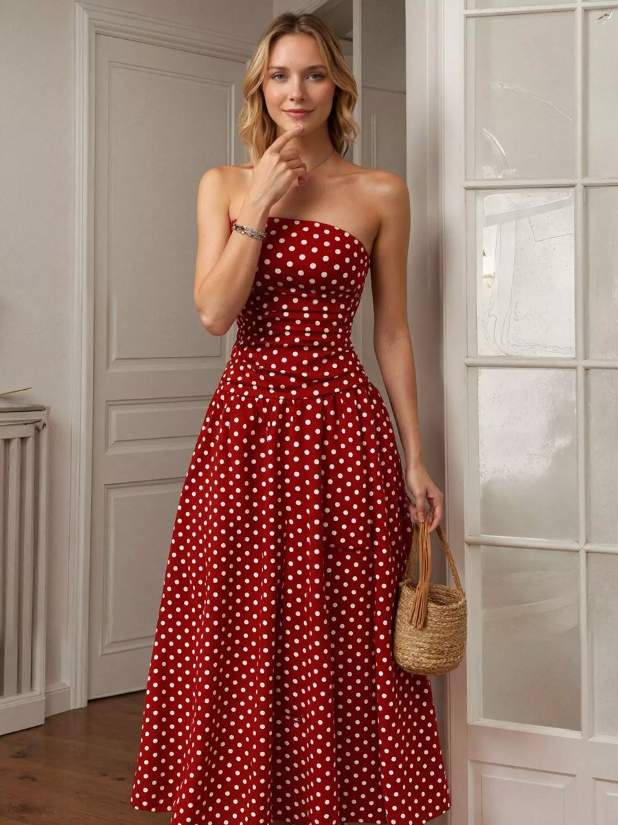 Woman wearing a red strapless dress with white polka dots indoors.