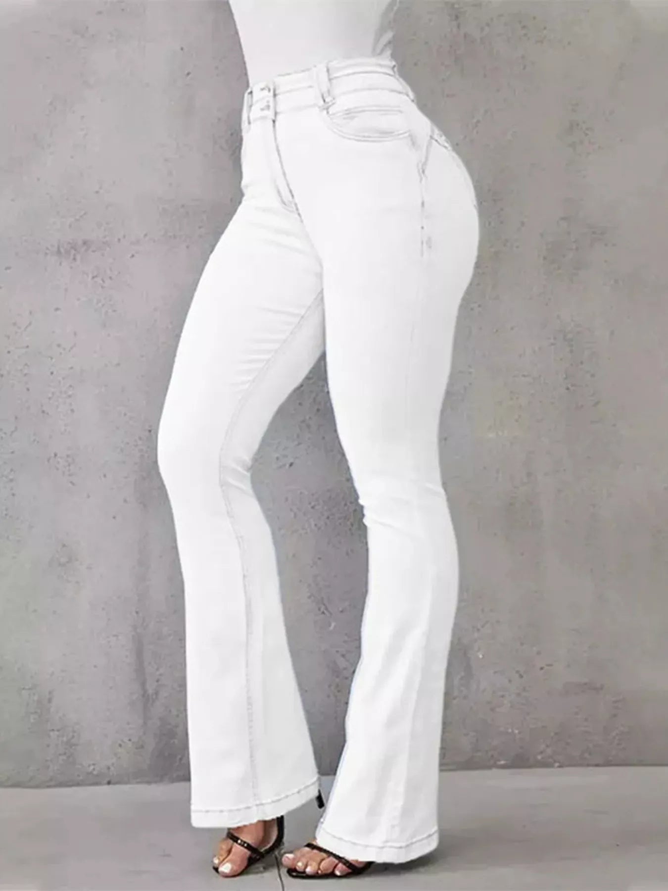 White flared jeans worn by a person on a gray background