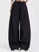 Black wide-leg pants with an elastic drawstring waist and front patch pockets, shown on a model from the back against a light gray studio background.