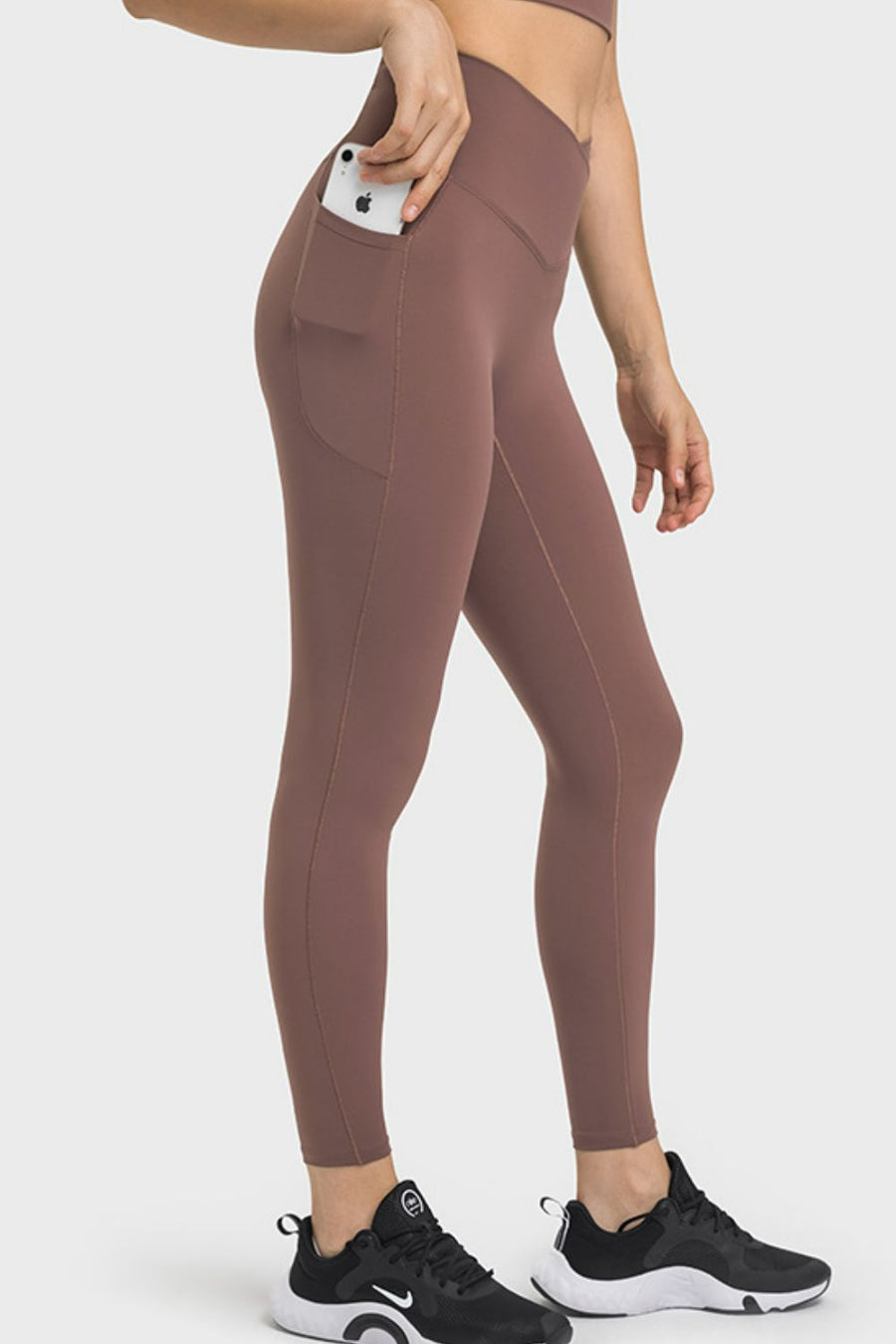 Brown leggings with pockets worn by a person on a white background