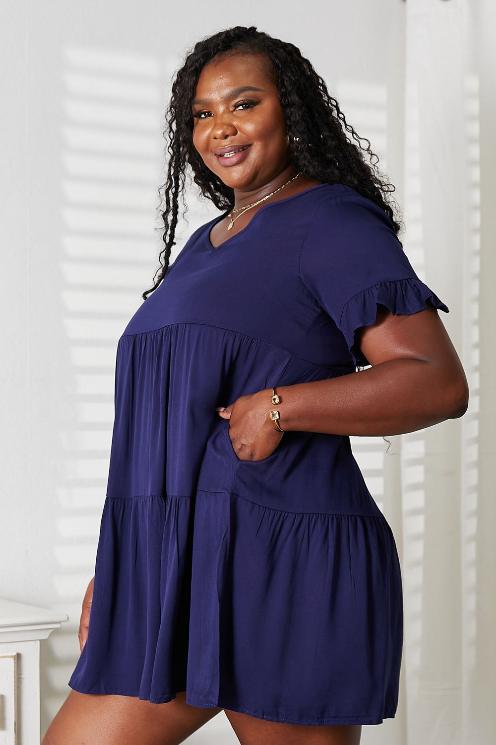 Woman wearing a navy blue dress with ruffled sleeves against a white background