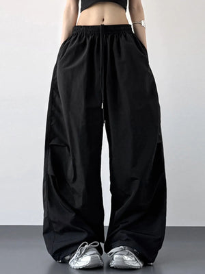 Person wearing black wide-leg pants with a plain background