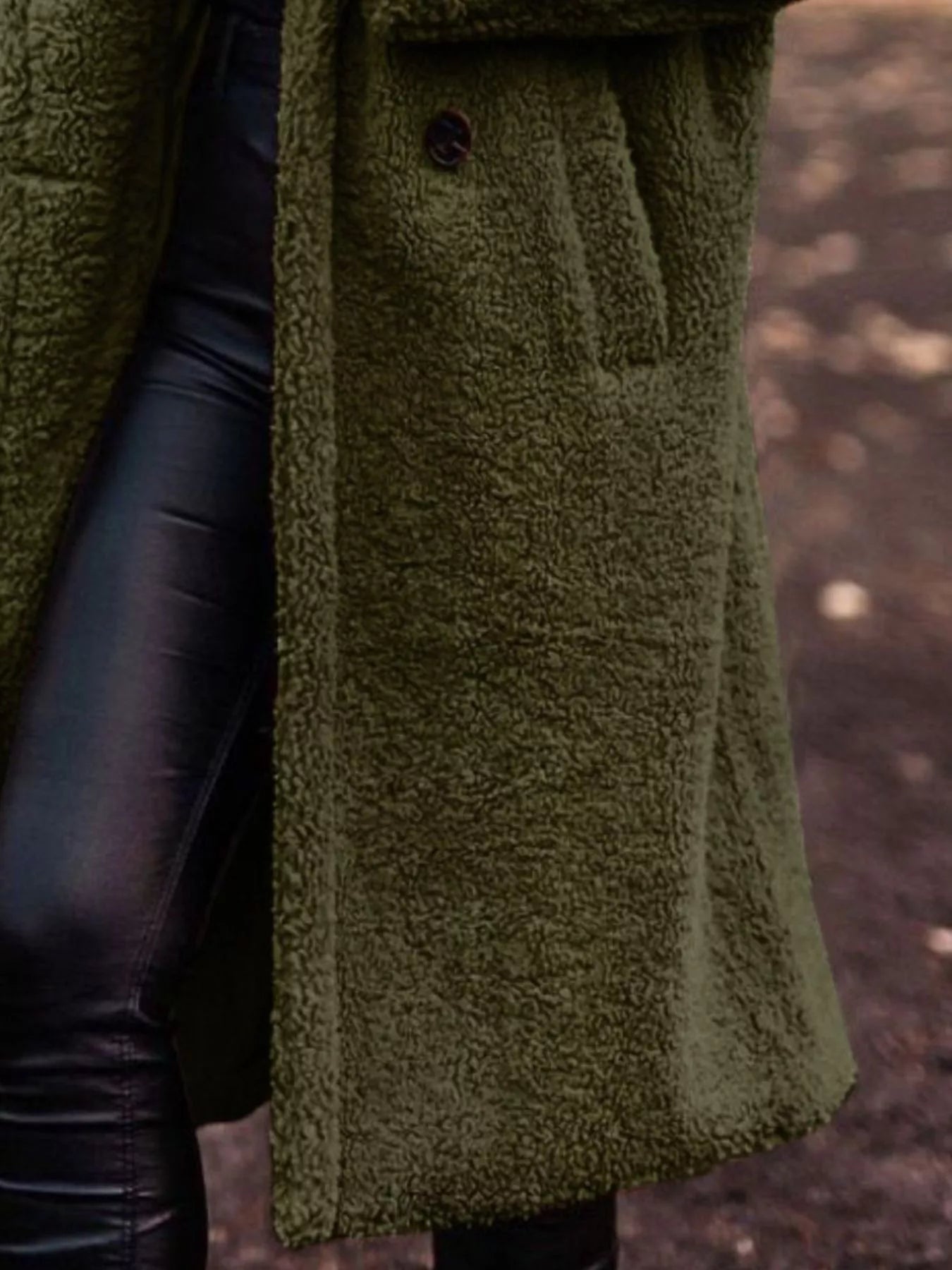 Green textured coat with leather sleeves against a blurred natural background