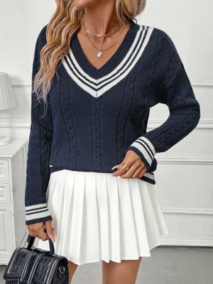 Woman wearing a navy sweater with white stripes and a white pleated skirt.