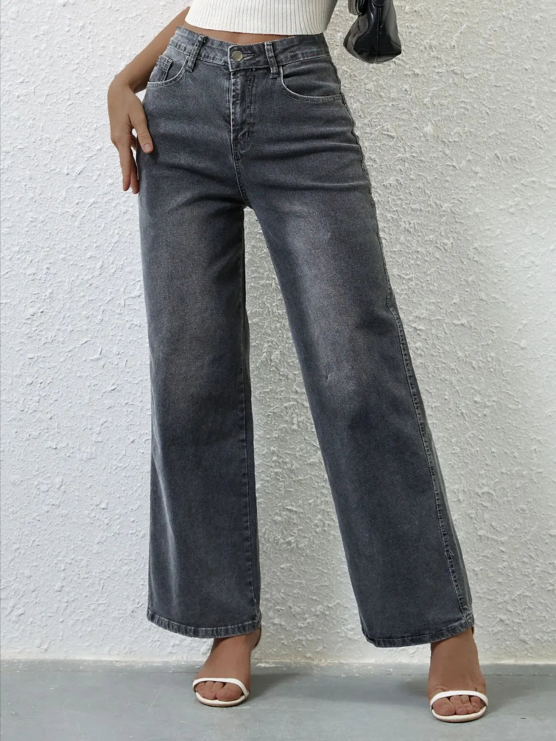 Person wearing high-waisted black jeans against a light gray background