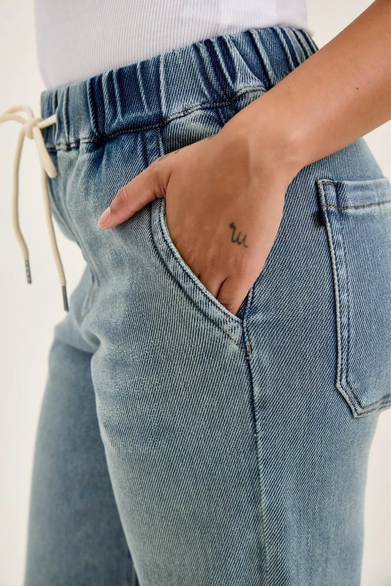 Close-up of blue jeans with a hand in the pocket on a plain background