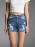 Person wearing blue denim shorts with slight distressing on a gray background