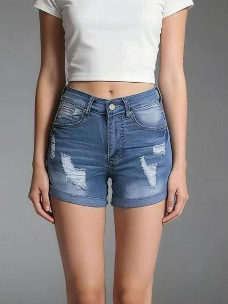 Person wearing blue denim shorts with slight distressing on a gray background