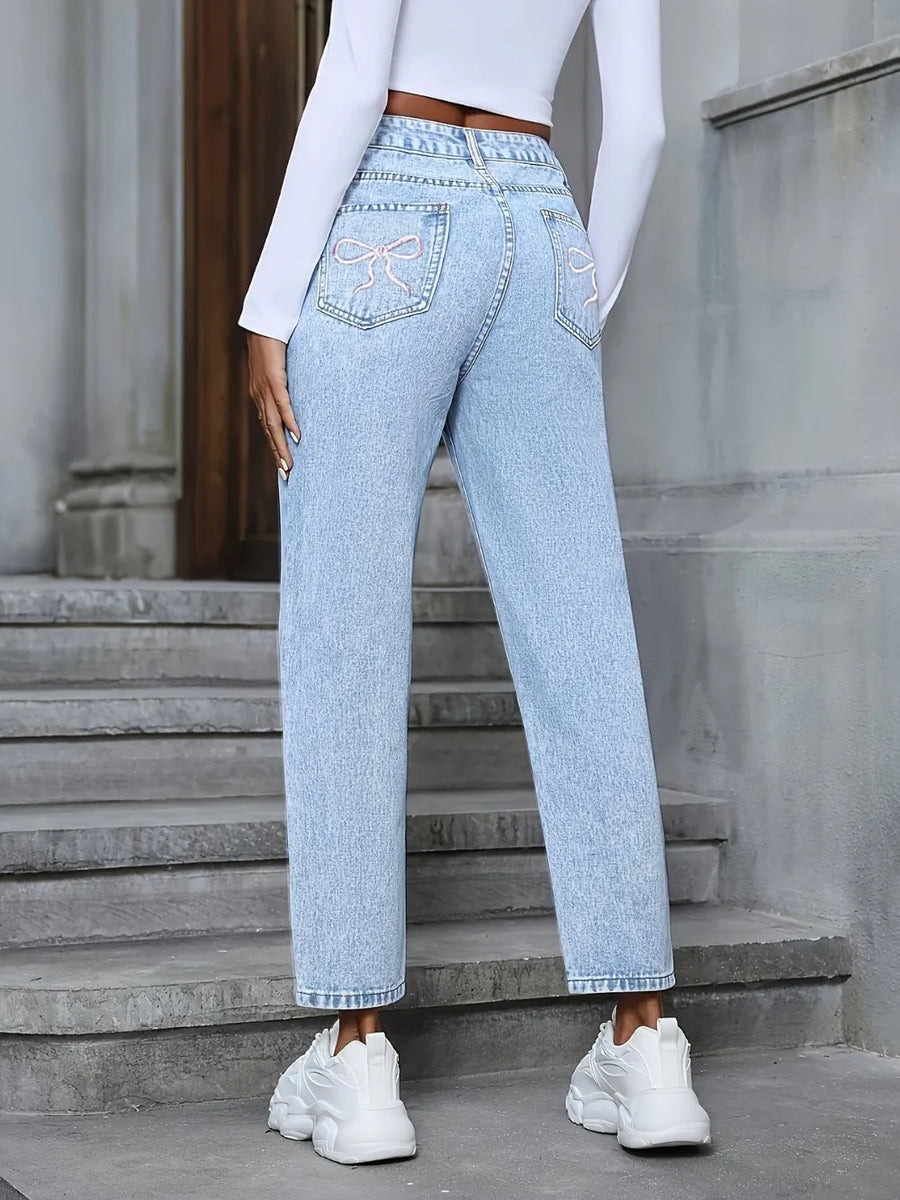 Person wearing light blue jeans and white sneakers standing on steps.