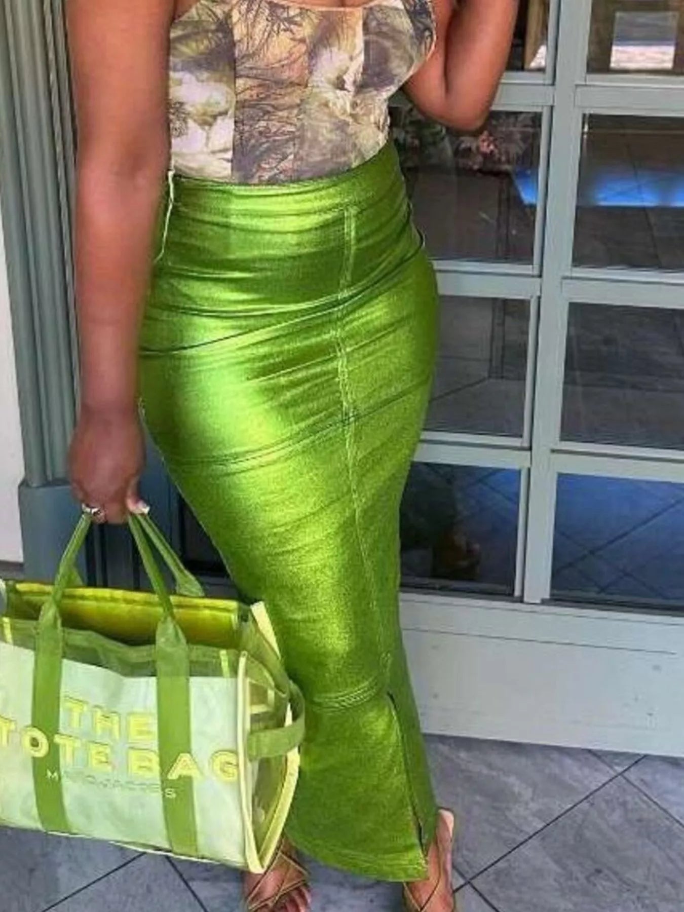 Person wearing a green satin skirt holding a green tote bag.