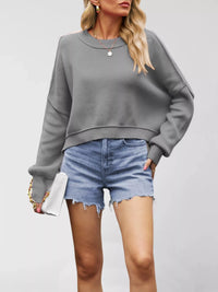 Woman wearing a gray sweater and denim shorts on a plain background