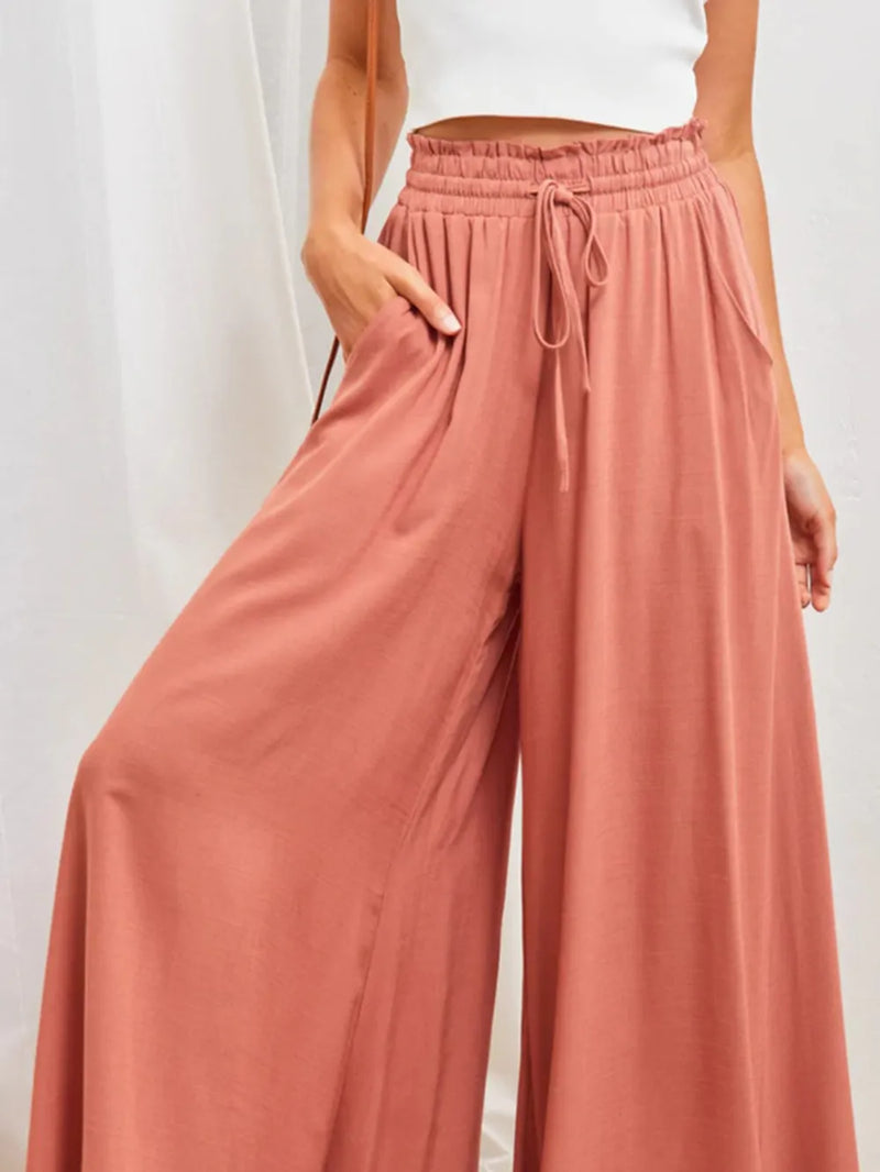 Person wearing pink wide-leg pants with a white background