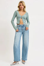 Woman wearing a light blue cardigan and jeans on a white background