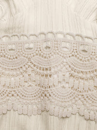 Close-up of intricate lace fabric with a neutral color palette.