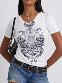 Person wearing a white t-shirt with black intricate design, standing against a plain background