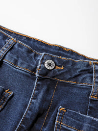 Close-up of blue denim jeans with a button and stitching detail on a white background