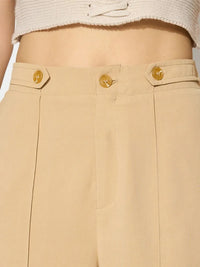 Beige pants with gold buttons on a neutral background