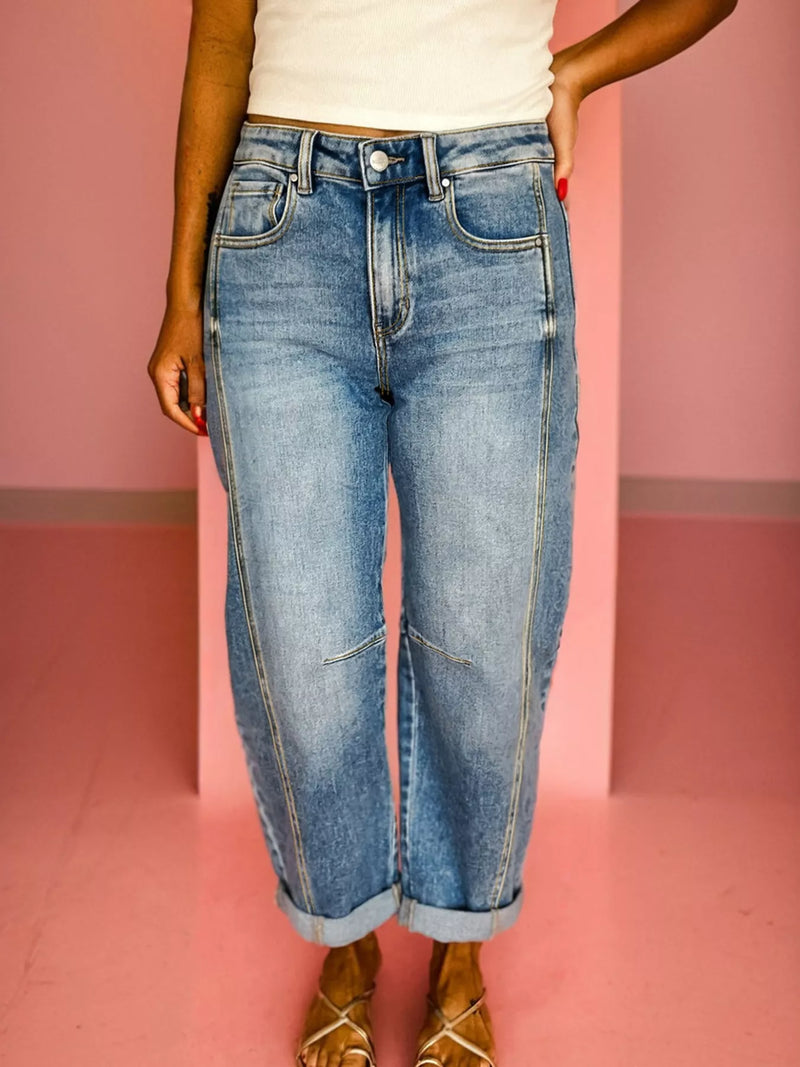 Person wearing blue jeans against a pink background