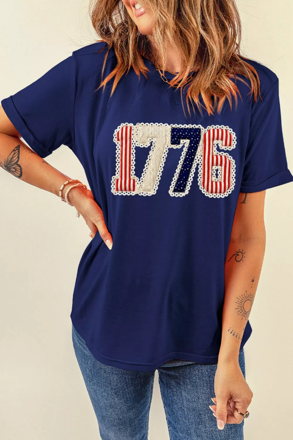 Person wearing a navy blue t-shirt with '1776' printed on it, standing against a plain background.