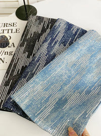 Two textured fabric samples, one black and white patterned and one blue and white patterned, on a white surface.