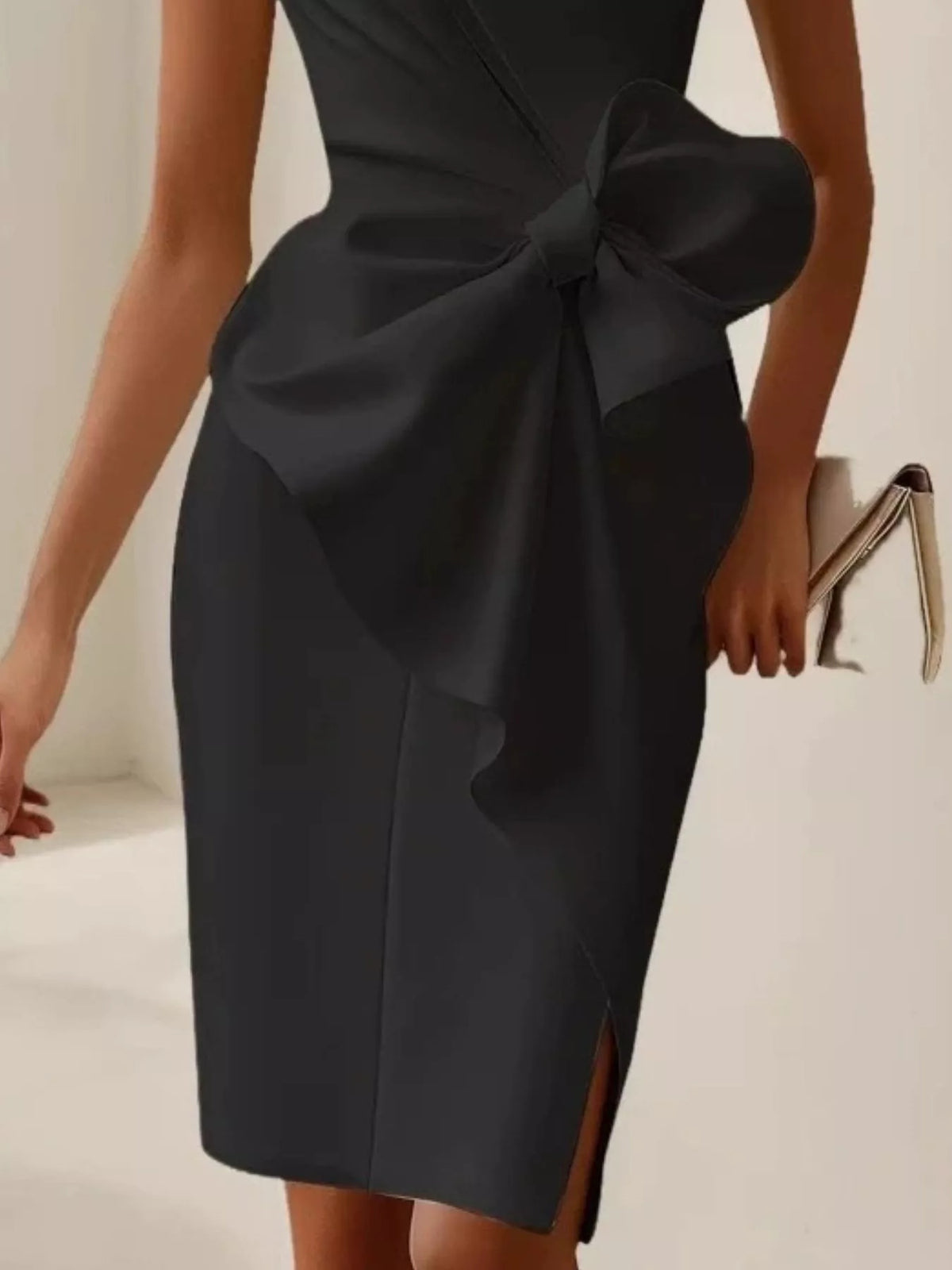 Black dress with a large bow detail on a neutral background