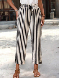 Person wearing black and white striped pants on a blurred outdoor background