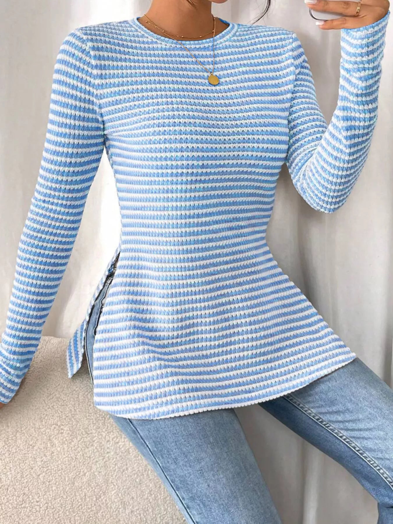 Person wearing a blue and white striped sweater and jeans against a neutral background
