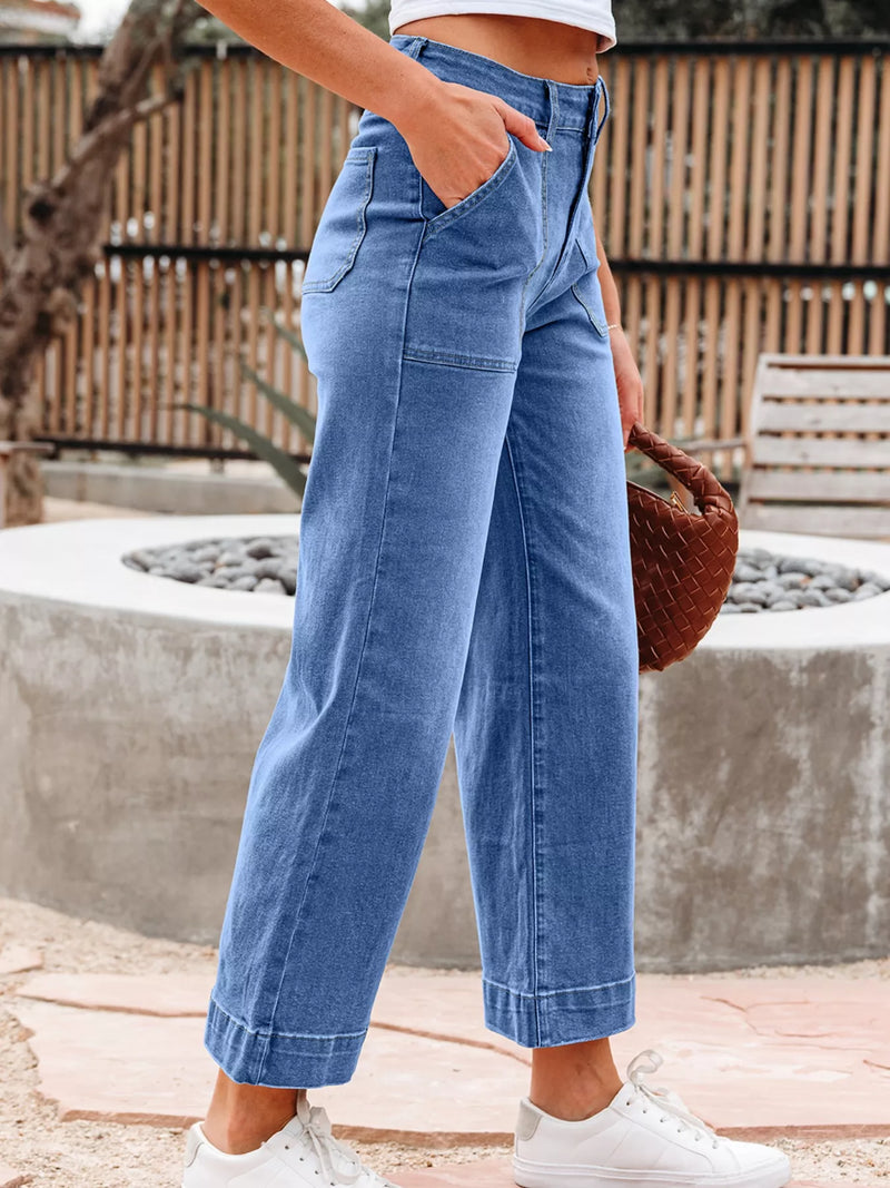 Person wearing blue wide-leg jeans with a blurred background
