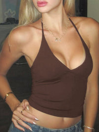 Woman wearing a brown halter top and blue jeans indoors.