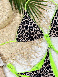 Leopard print bikini with green straps on a textured surface