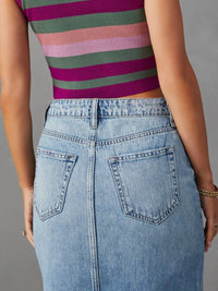 Person wearing a striped shirt and denim skirt on a gray background