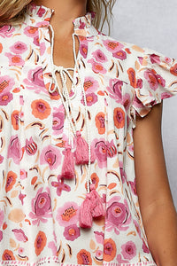 Floral blouse with pink tassels on a neutral background